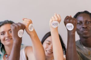 Selective Focus Photo of Vote Stickers on People's Fists