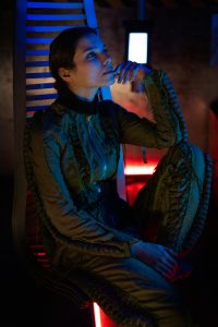 Computer & Sci-Fi System Voice Actor sitting in a black suit with red lights surrounding them